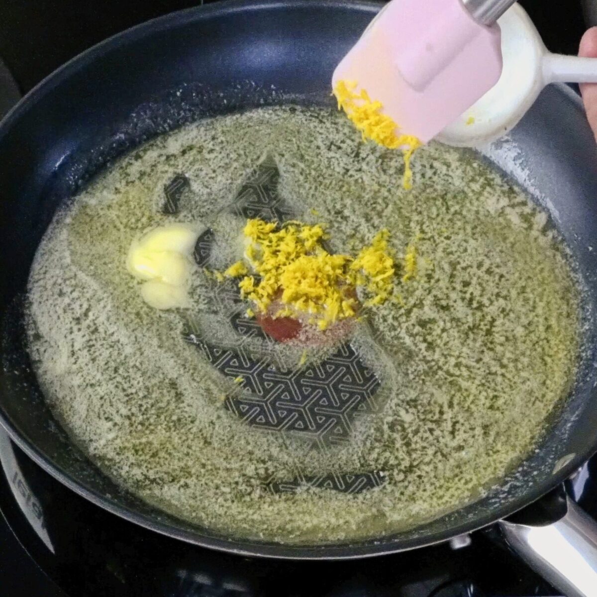 Adding lemon zest to melted butter in a pan.