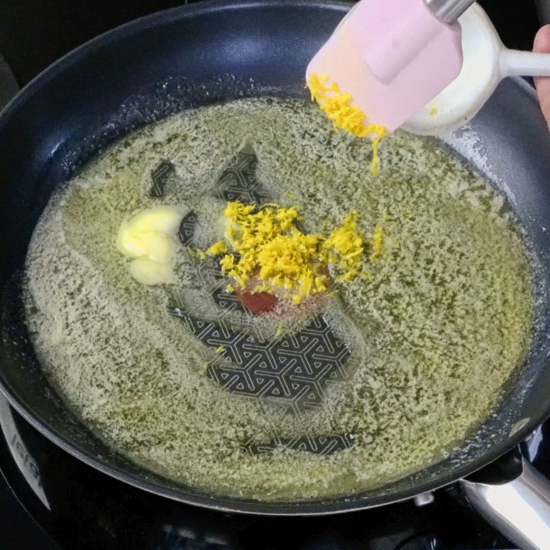 Adding lemon zest to melted butter in a pan.