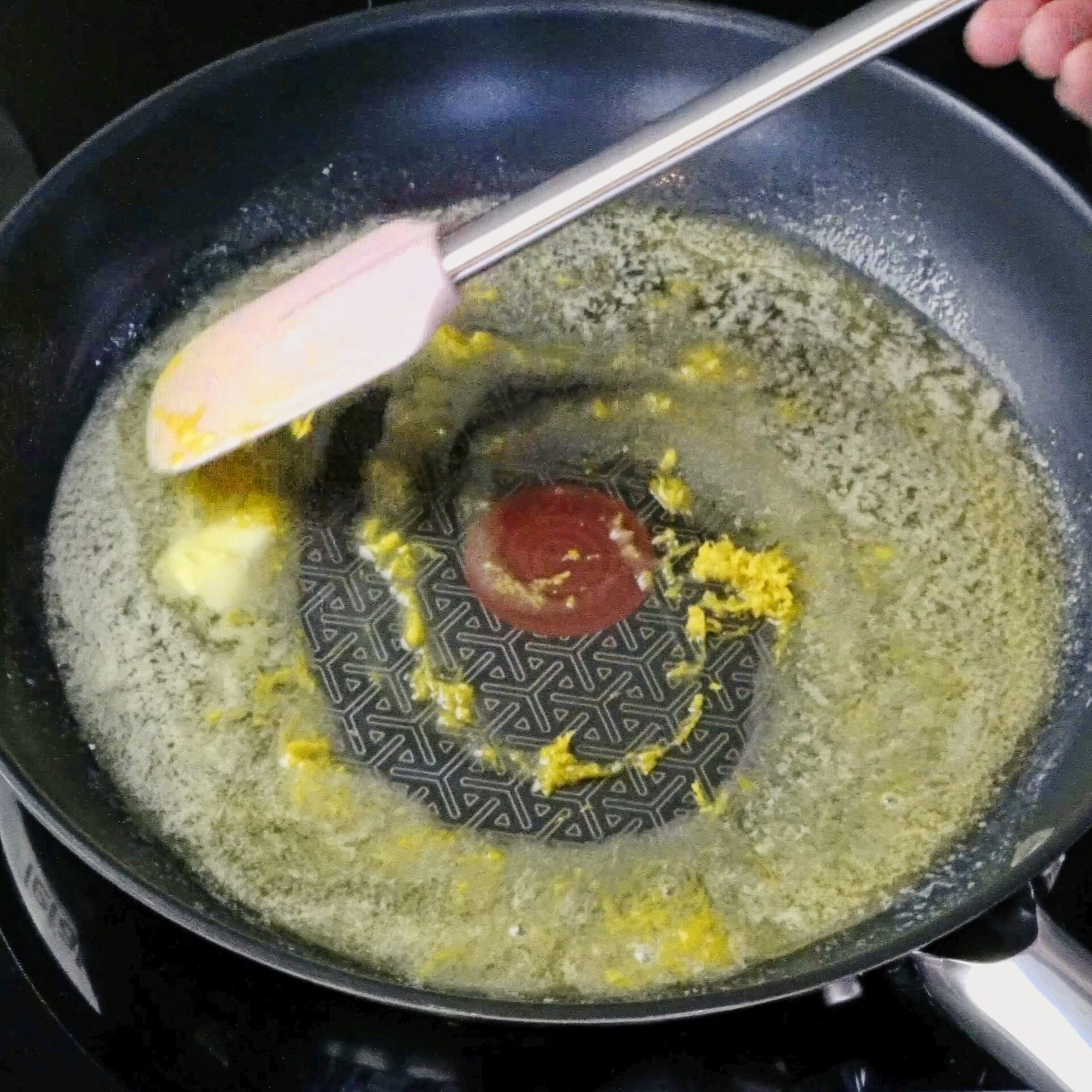 Stirring lemon zest into melted butter in a pan.