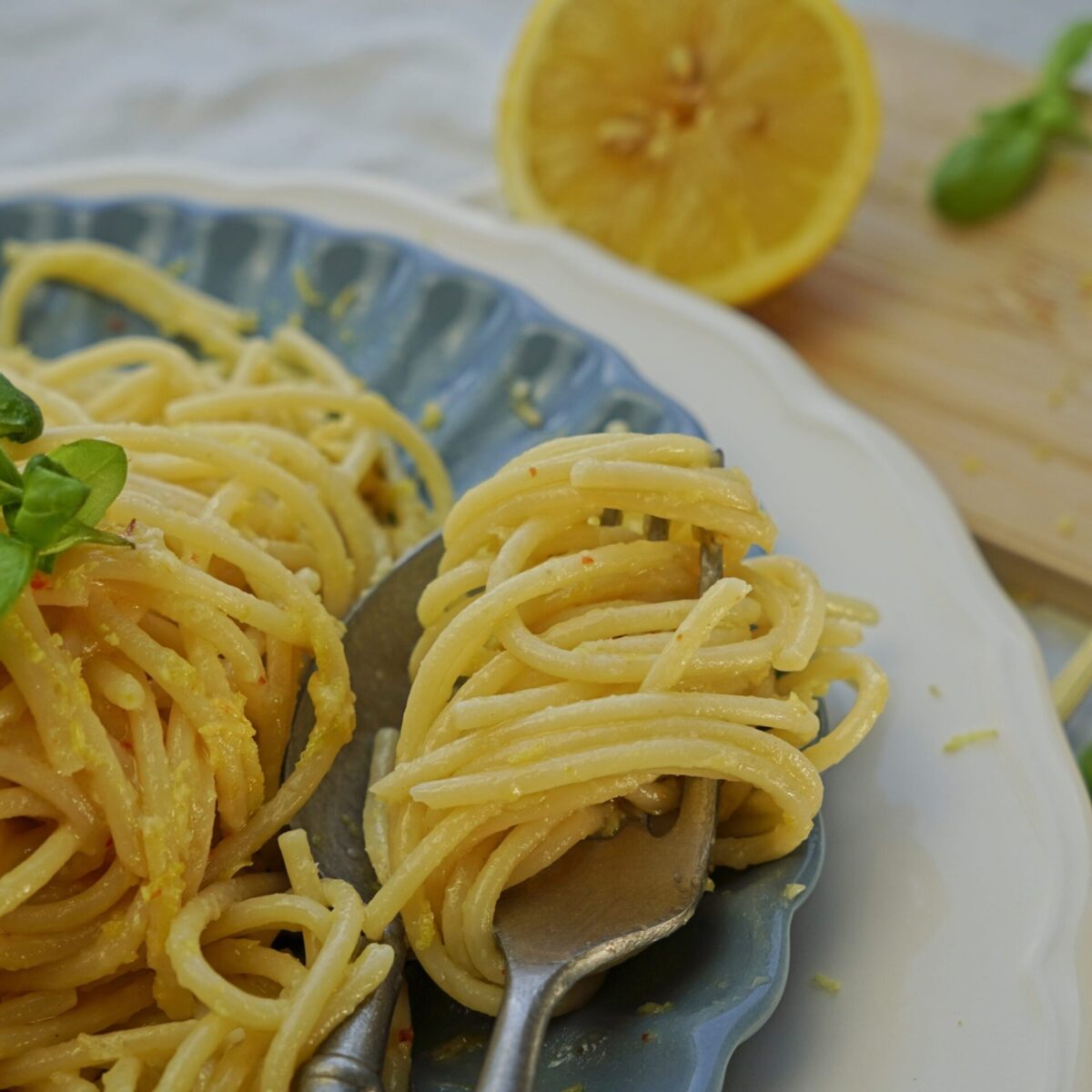 Close-up of al dente pasta twirled on a fork, coated in creamy lemon butter sauce.