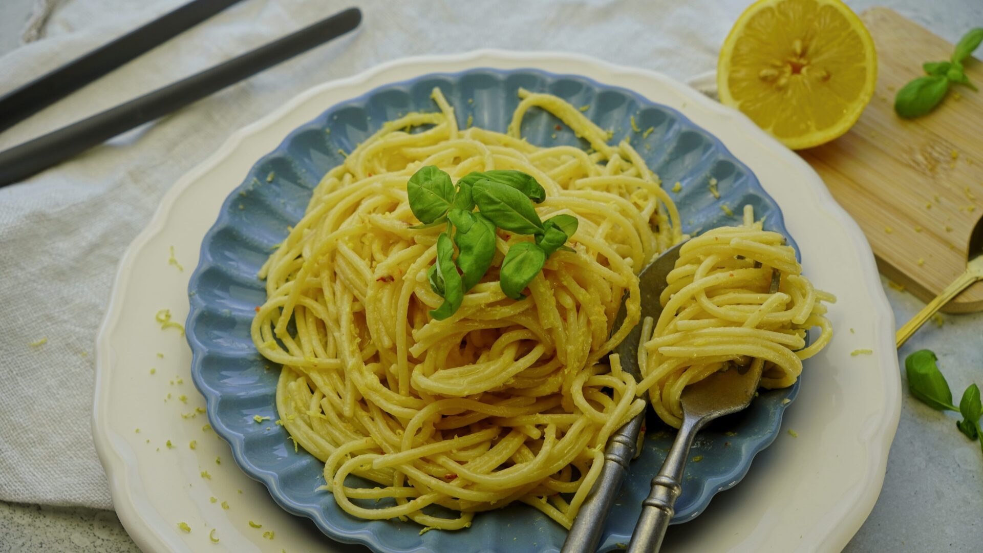 Creamy lemon butter pasta garnished with basil, with a fork placed on the right of the plate.