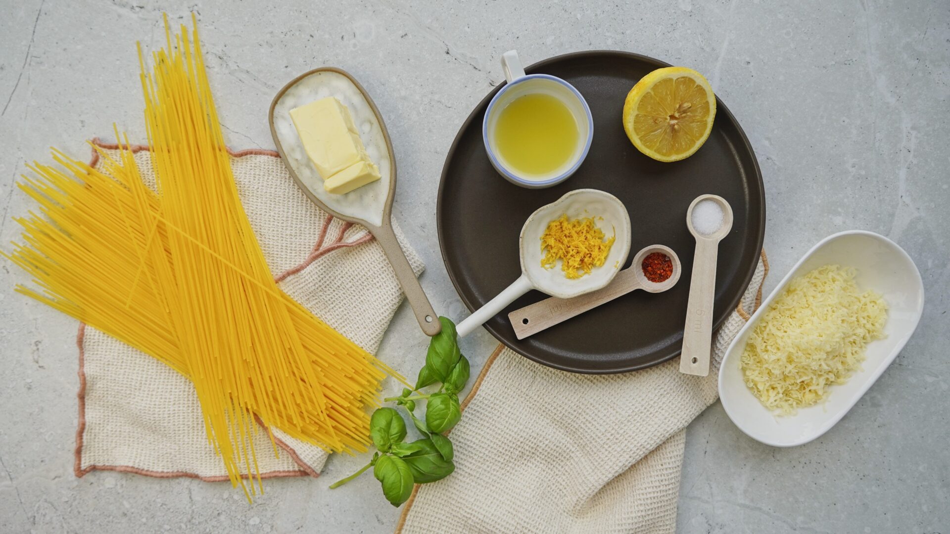 Ingredients for lemon butter pasta: pasta, butter, lemon zest, lemon juice, grated cheddar cheese, salt, and chili flakes.
