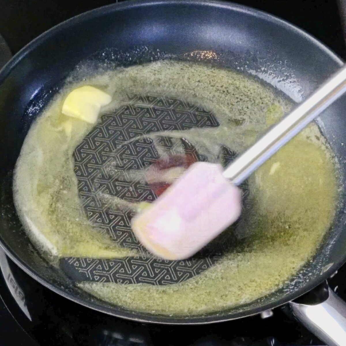 Stirring butter in a pan to help it melt evenly.