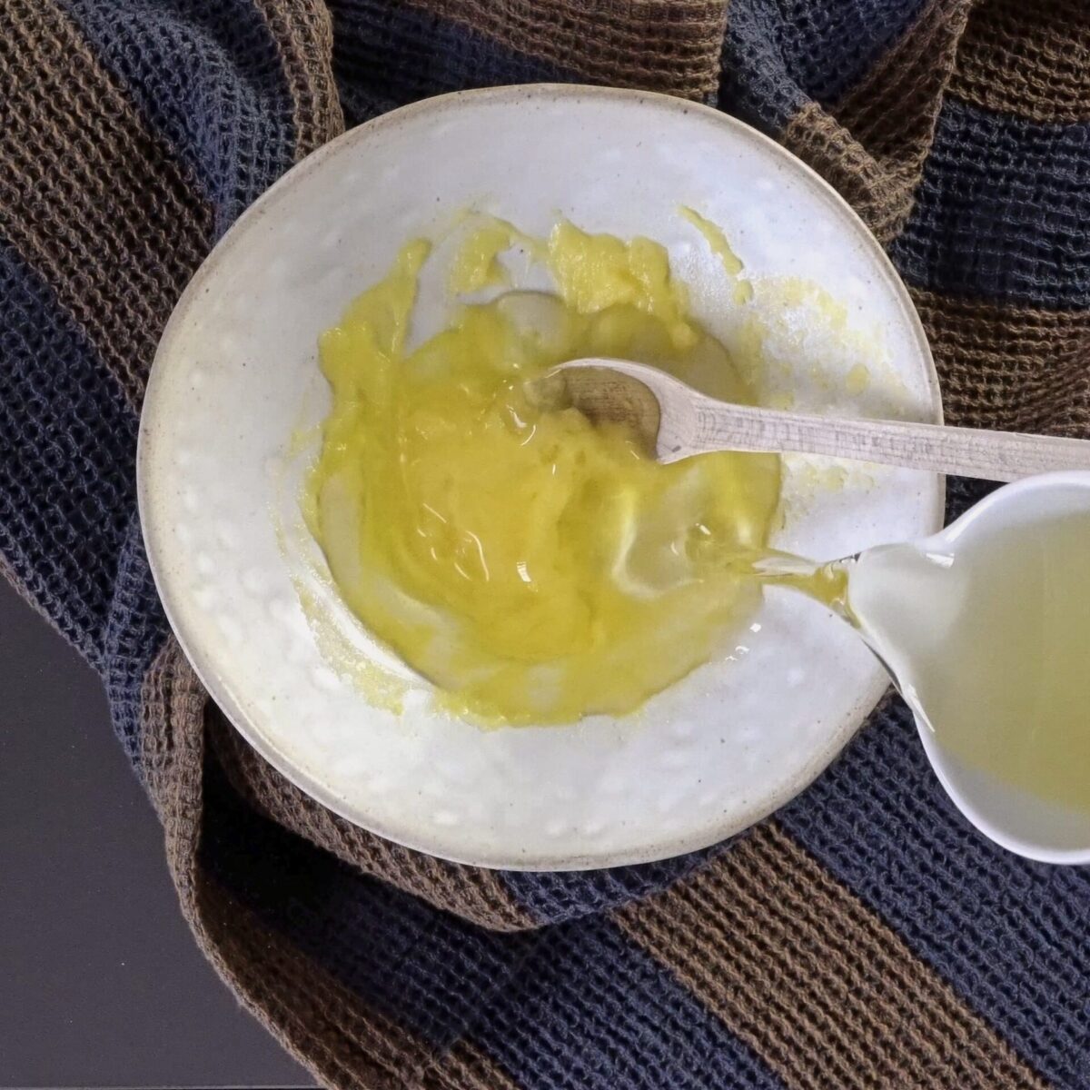 Pouring oil into softened butter to make a brushing mixture.
