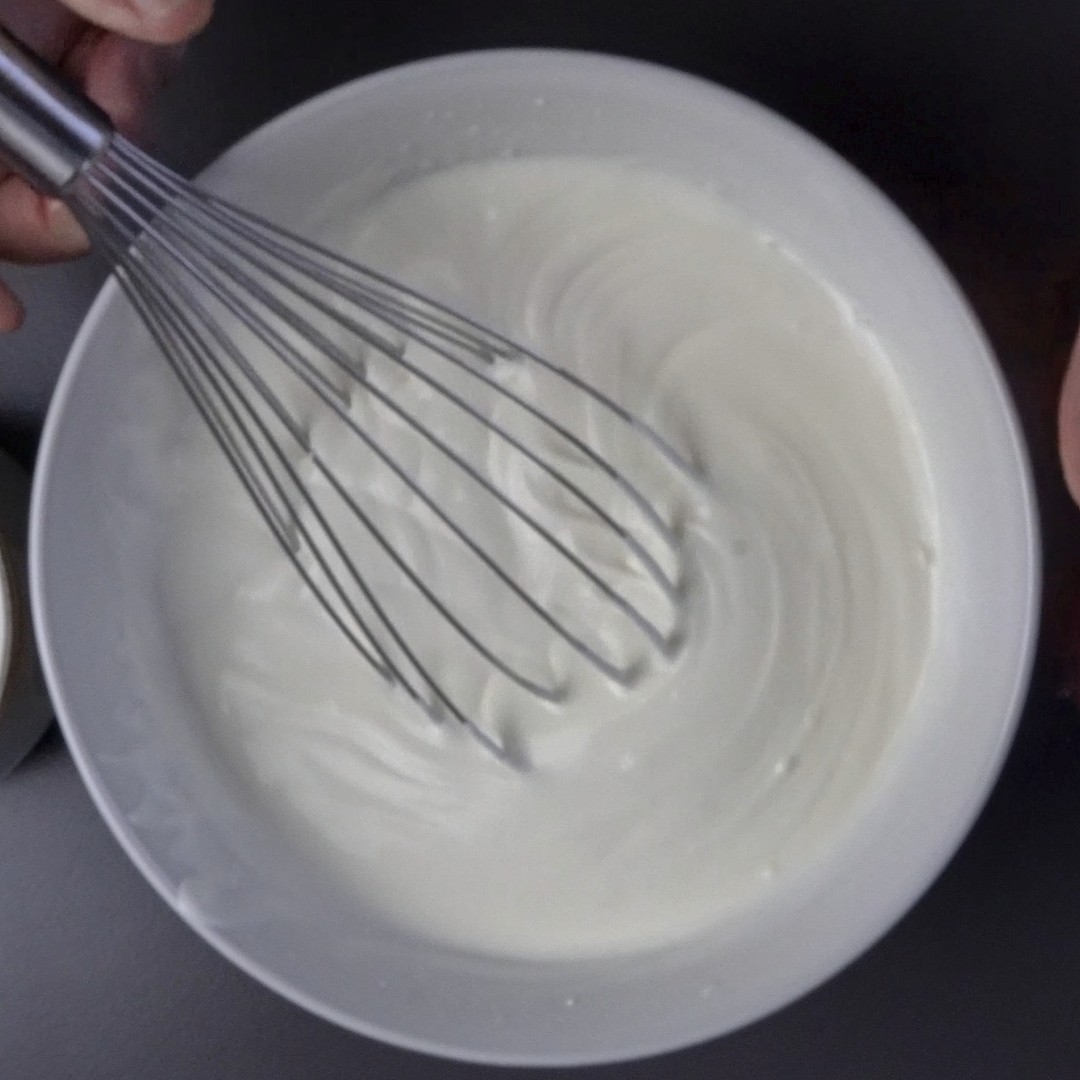 Stirring heavy cream and sour cream with a whisk until smooth.