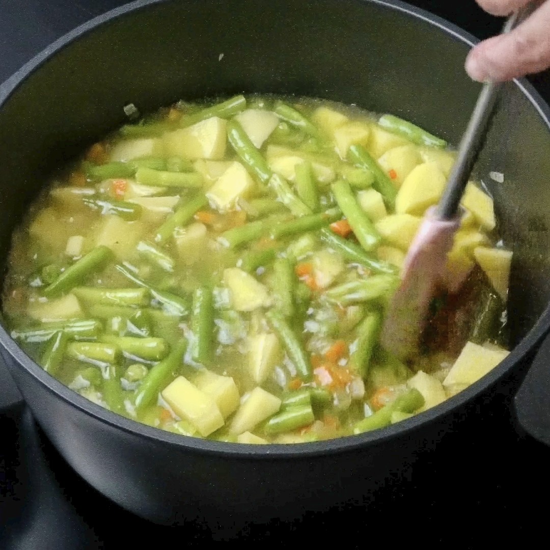 Stirring vegetables and stock together in the pot.