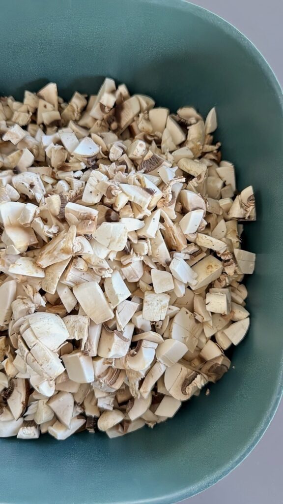 Mushrooms cut into cubes in a green bowl.