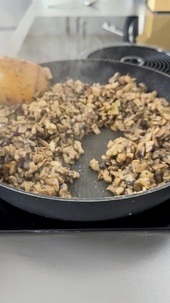 A person is showing that there is no liquid left in a pan with fried mushrooms.