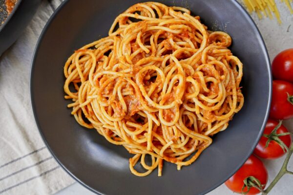 Pasta and tomato sauce on a grey plate. The sauce has rich and thick consistency.