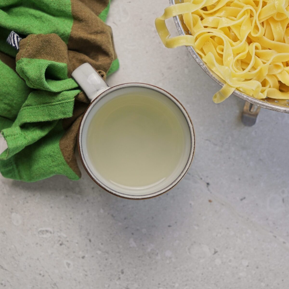 Pasta water in a cup, ready to add into the sauce.