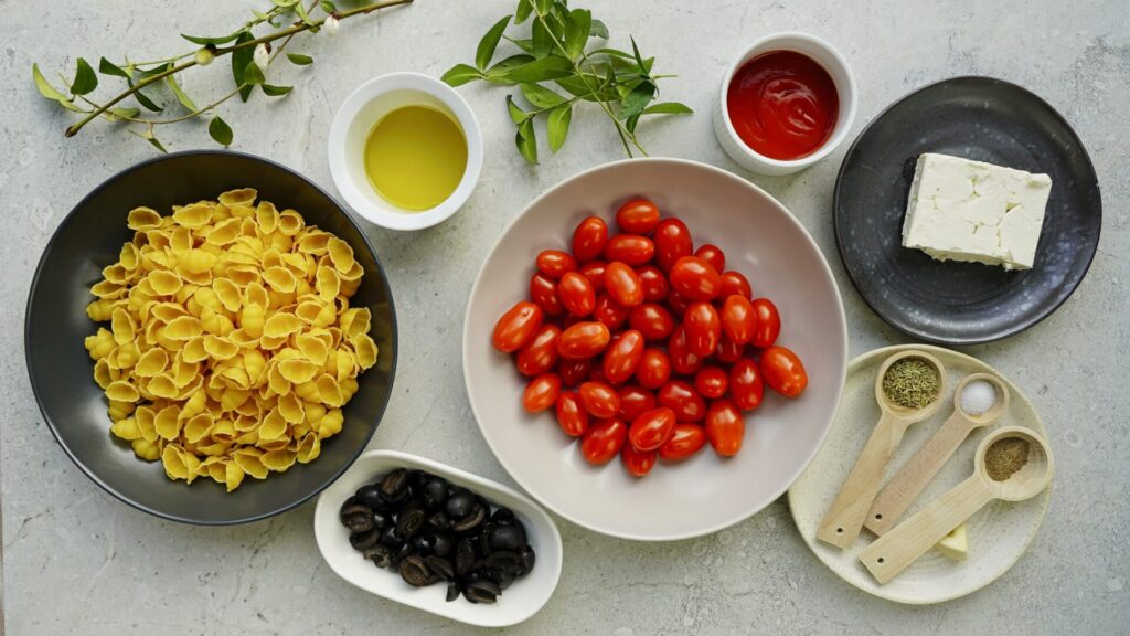 Ingredients for pasta with cherry tomatoes and feta cheese including pasta, feta cheese, cherry tomatoes, black pitted olives, passata, olive oil, rosemary, ground black pepper, salt, and garlic.