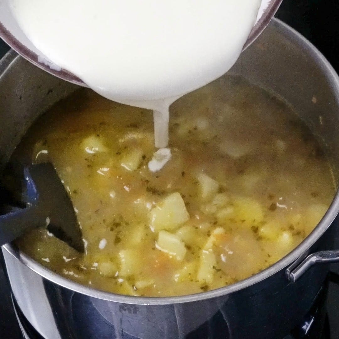 Pouring the heavy cream and flour mixture into the soup.