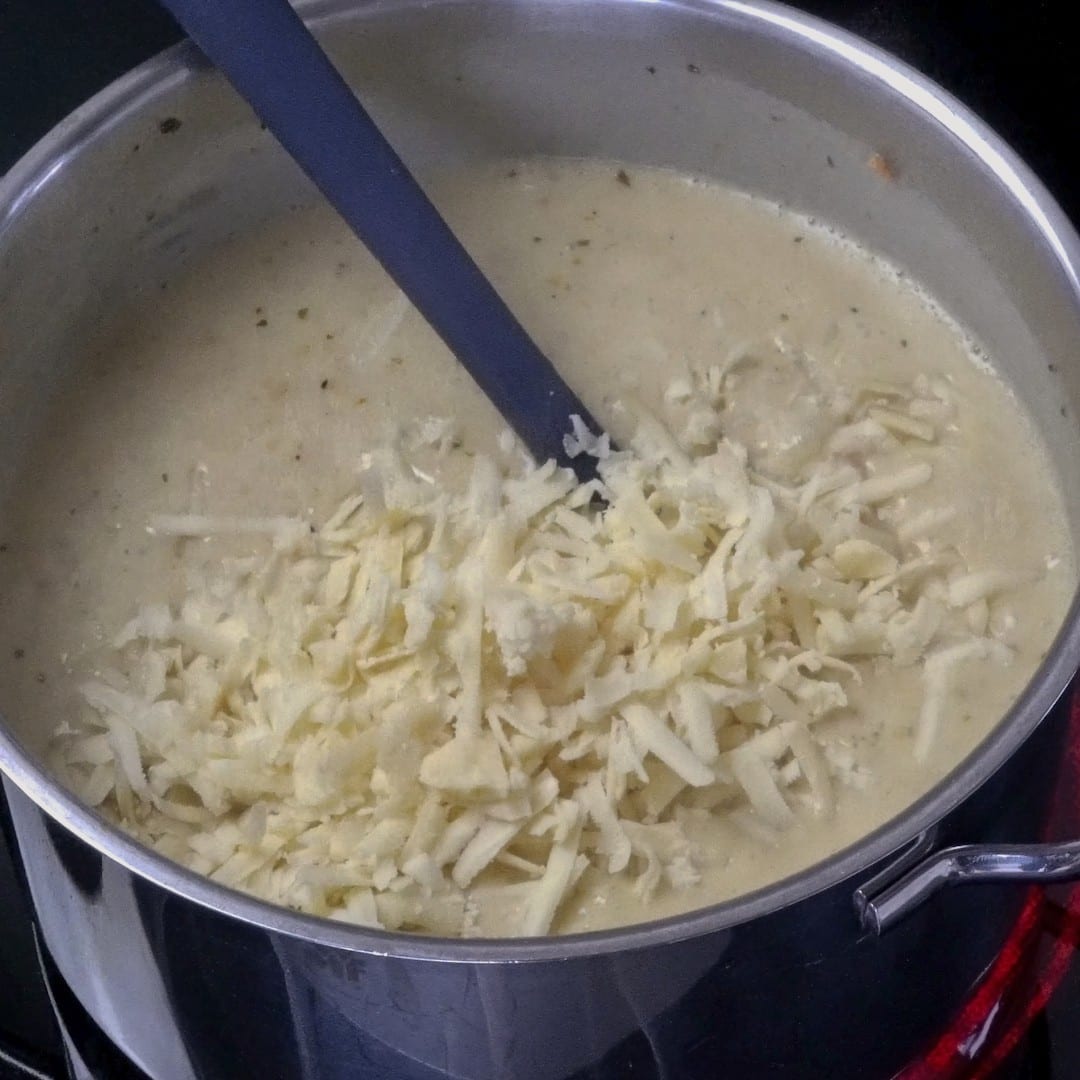 Stirring cheese into the potato soup until melted and creamy.