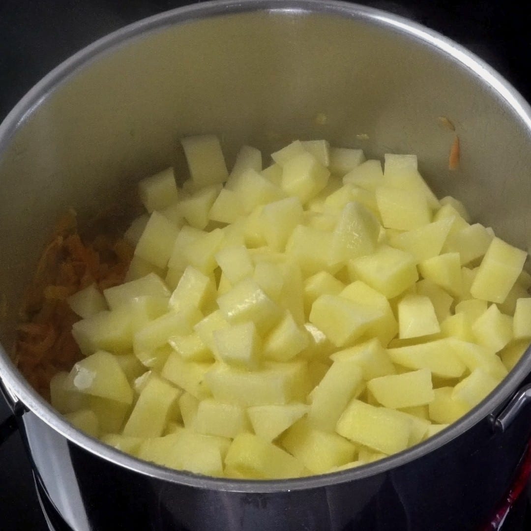 Adding potatoes to the pot.