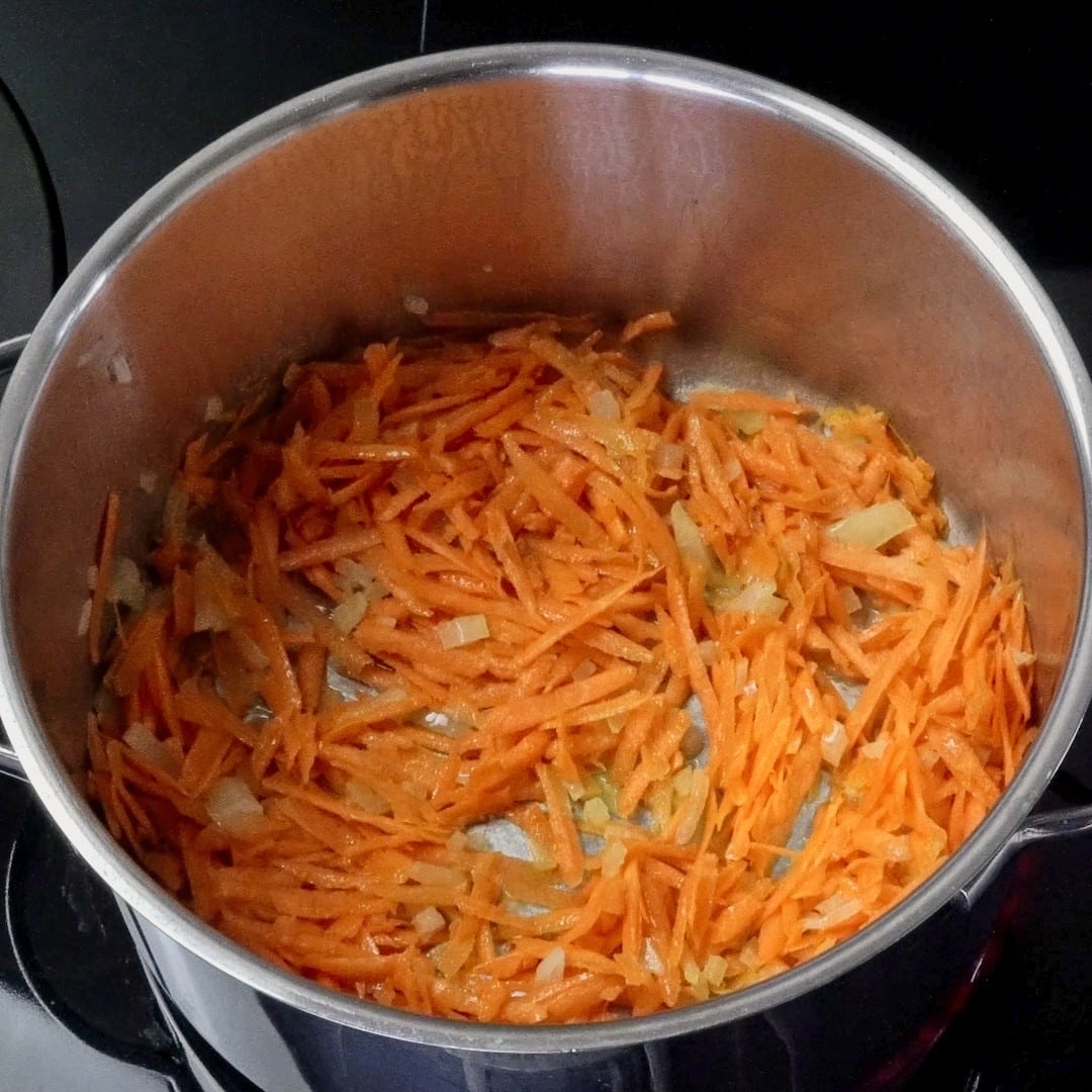 Sautéing carrots and onions in a pan.