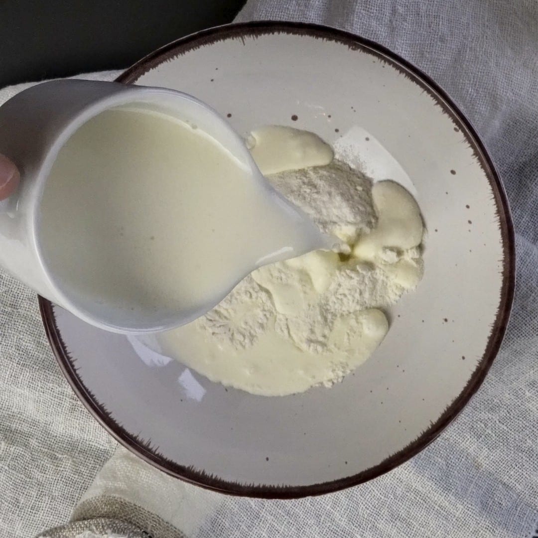 Mixing heavy cream with flour to create a creamy mixture.