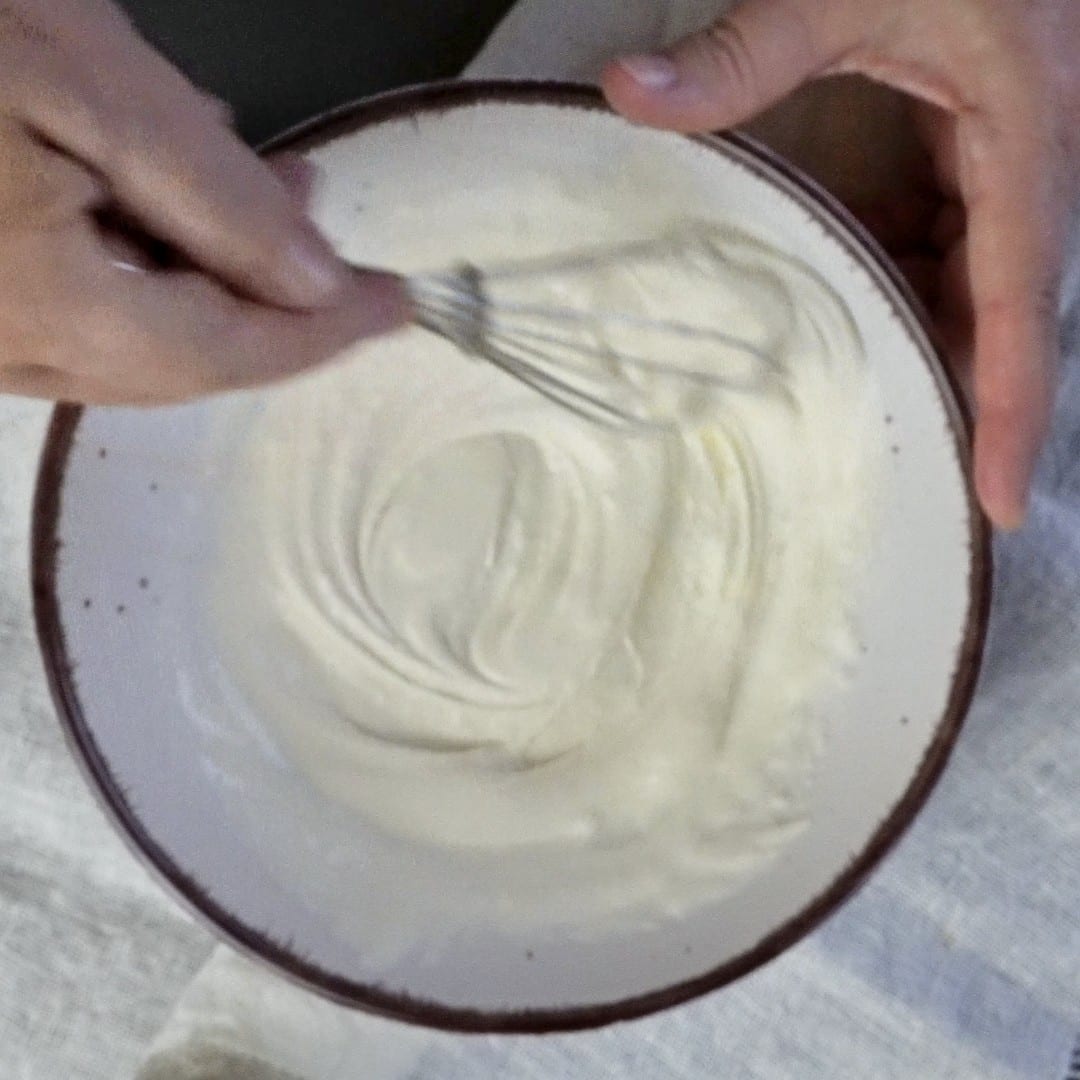 Mixing heavy cream and flour into a smooth, clump-free mixture.