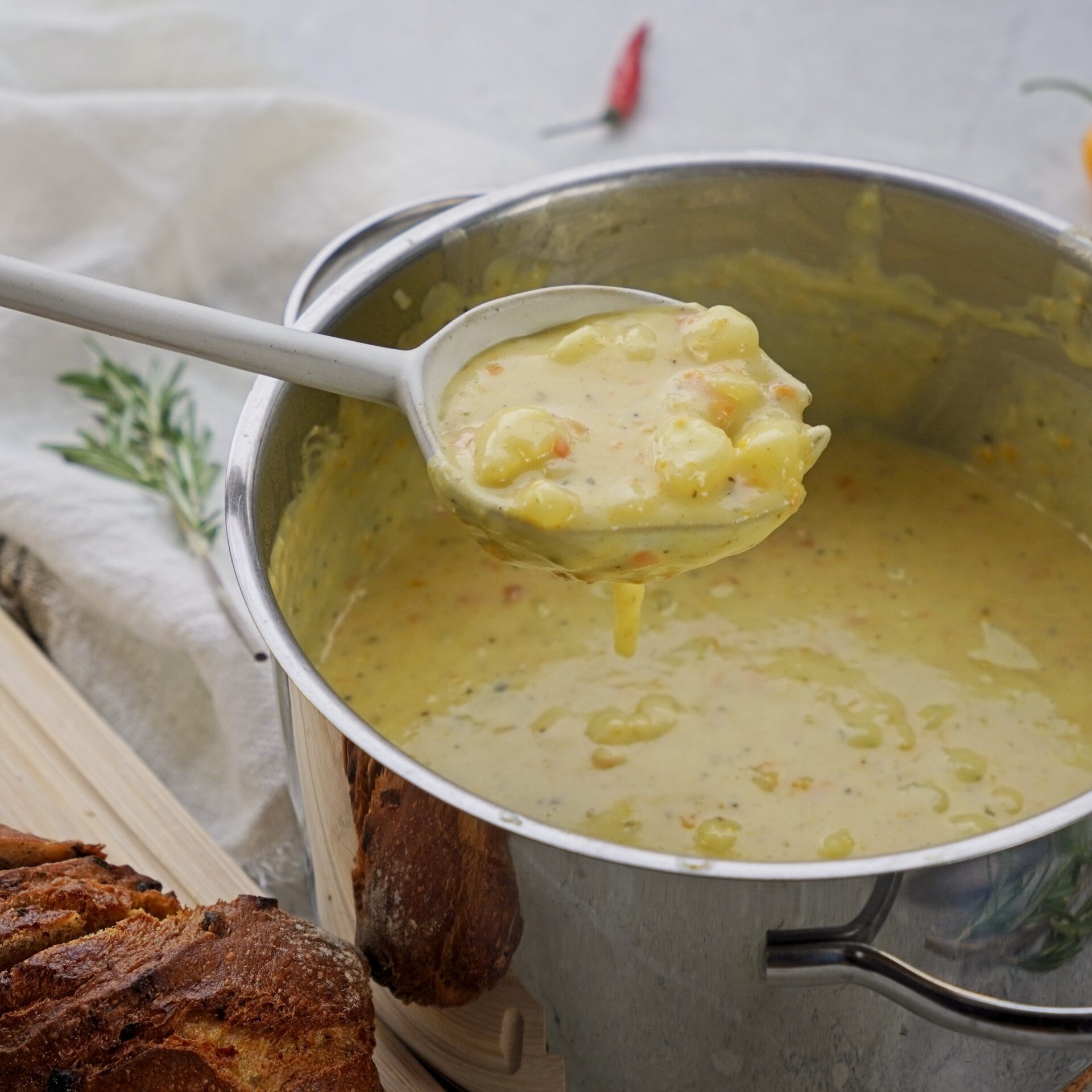 Ladle full of cheddar potato soup held over a pan of creamy soup.