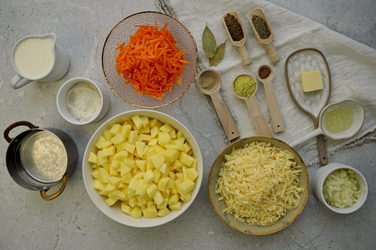 Ingredients you need for cheesy potato soup, cut and chopped: finely chopped onion, coarsely grated carrot, and potatoes cut into small pieces.