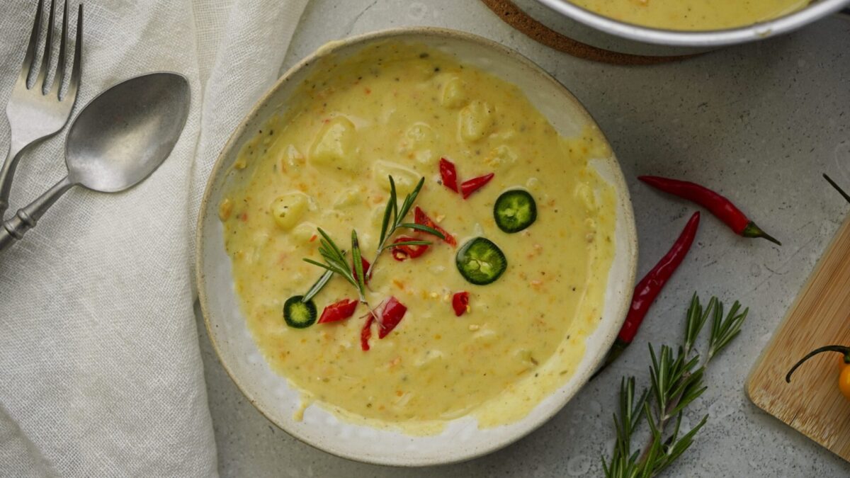 Bowl of potato cheese soup topped with red and green chili.