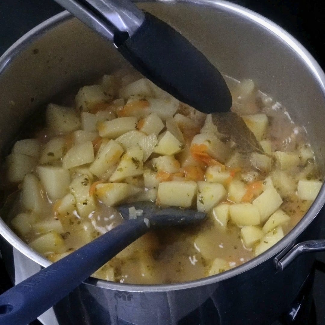 Removing bay leaves after the vegetables have softened.