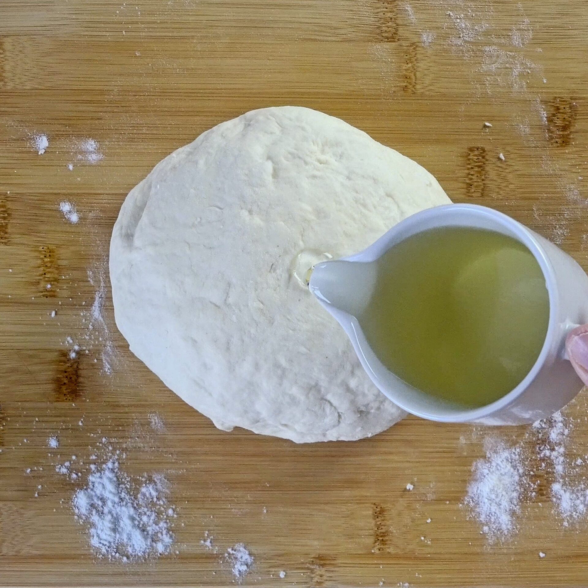 Pouring oil over the dough to keep it soft and prevent sticking.