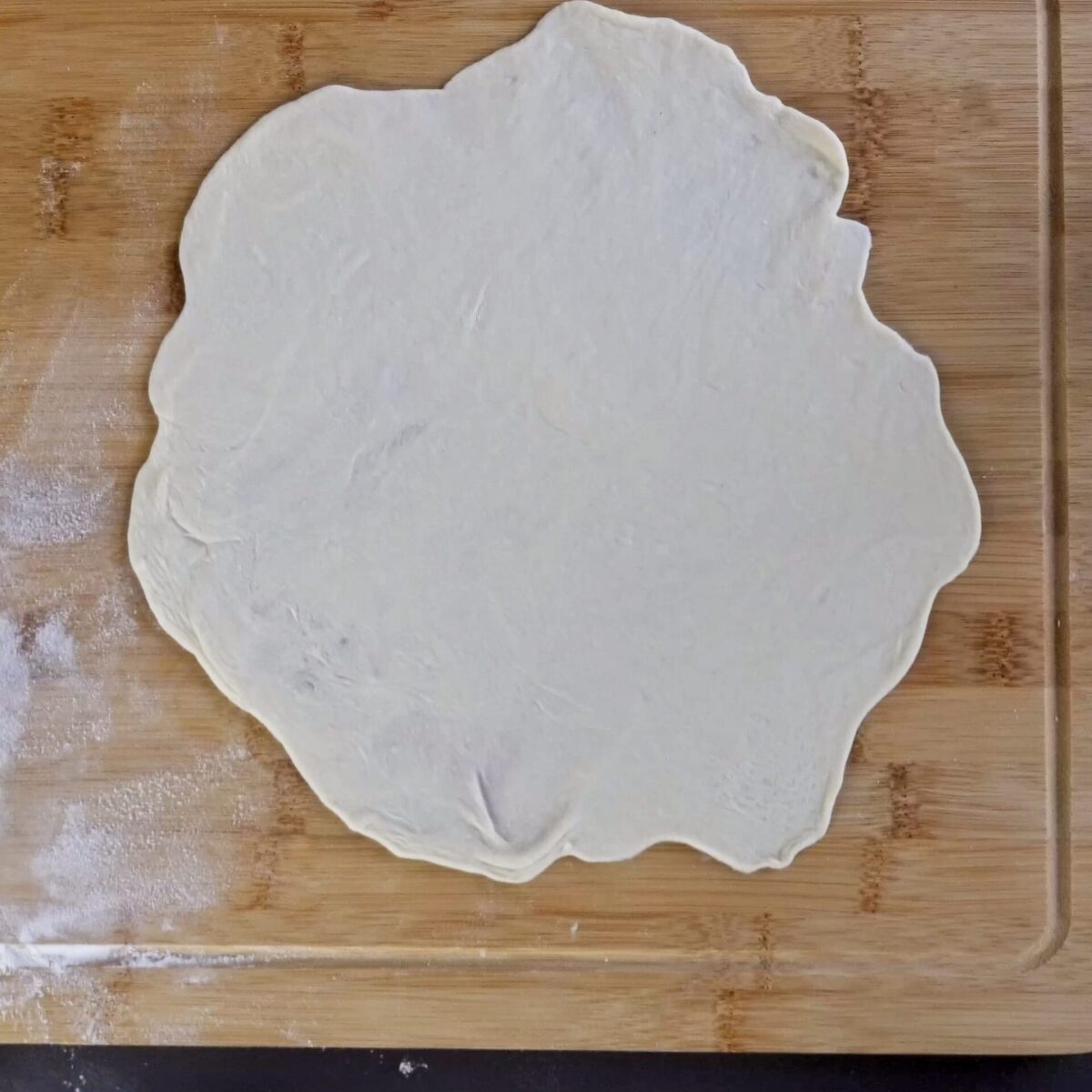 Thinly rolled roti dough, ready for cooking.
