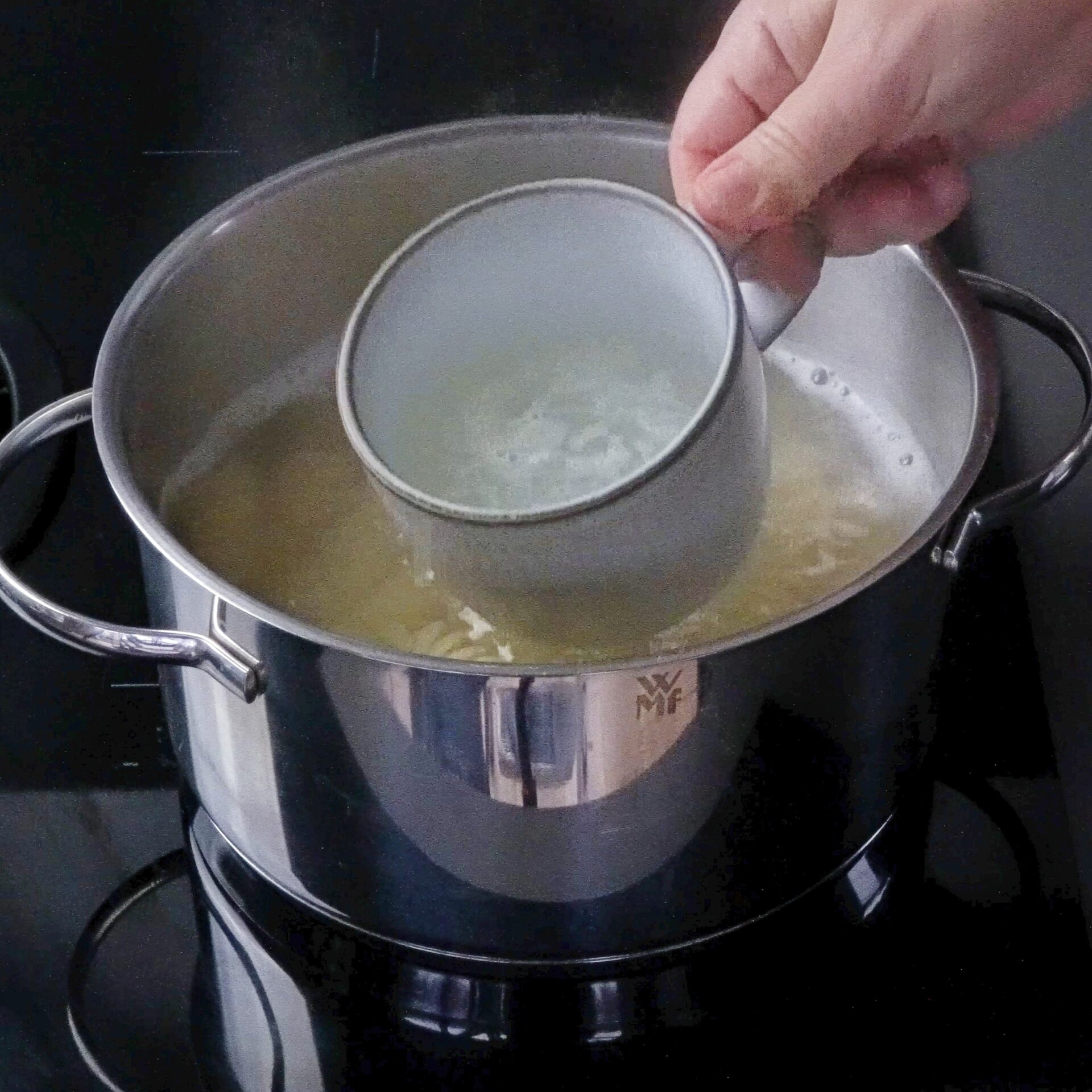 Scooping pasta water from the pot to use in the sauce.