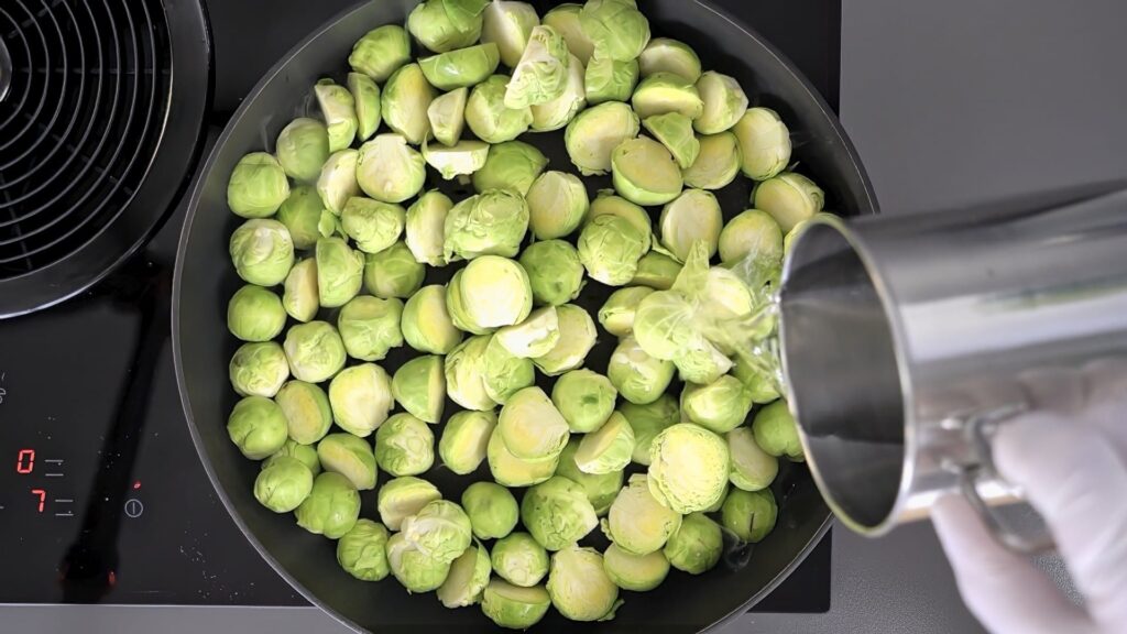 Pouring water into a pan with Brussels sprouts.