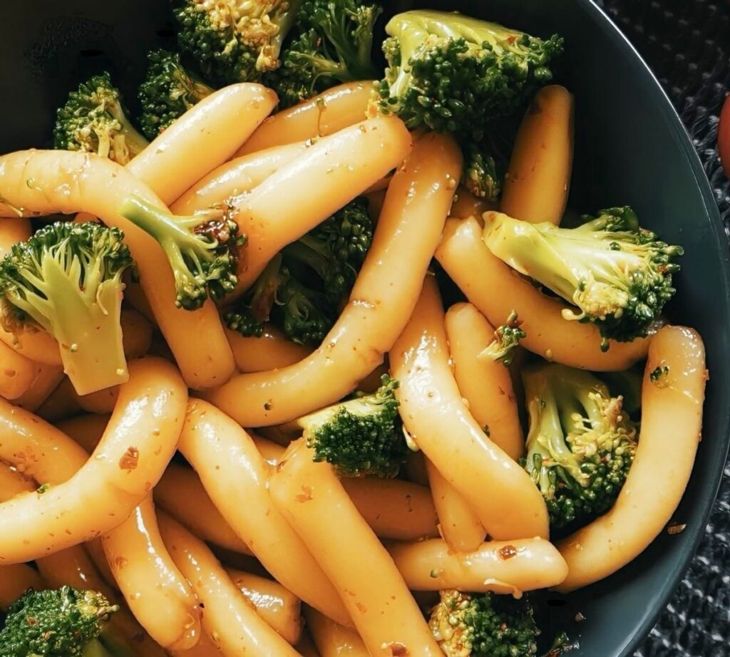 Thick potato noodles with broccoli and sauce in a plate.