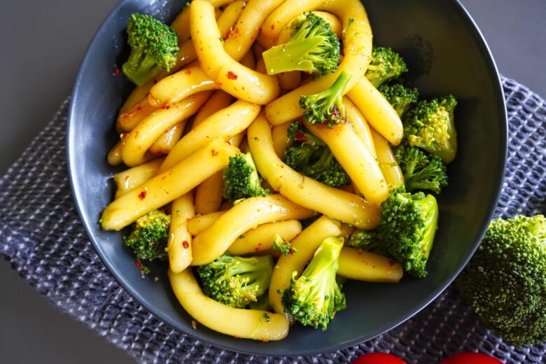 Spicy potato noodles with broccoli with sauce on plate. Thick and chewy!