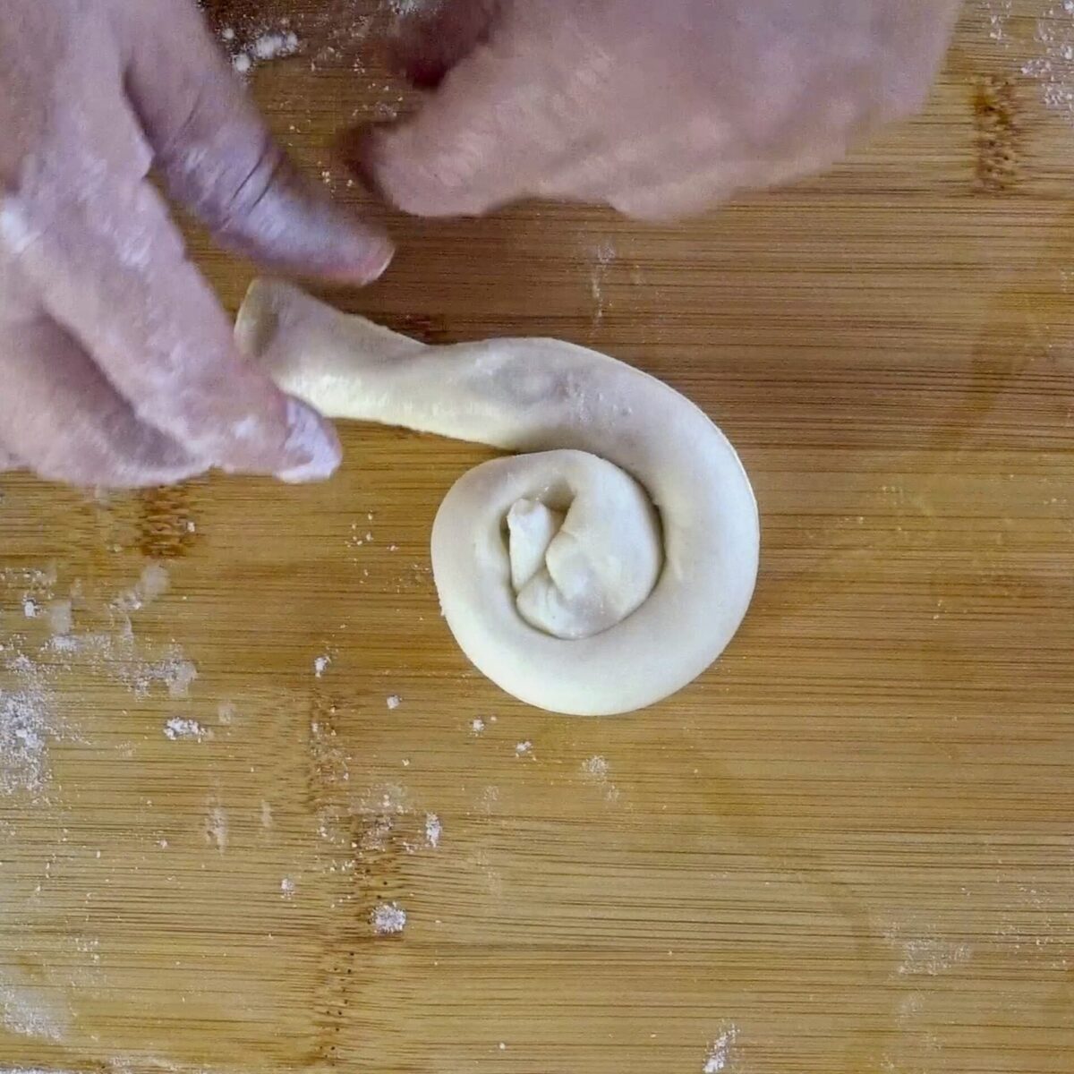 Twisting the dough log into a snail shape for layering.