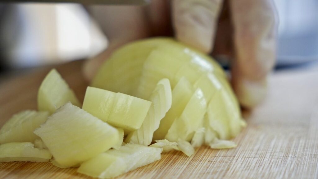 Cutting vegetables for the soup: chopping onions into large pieces.