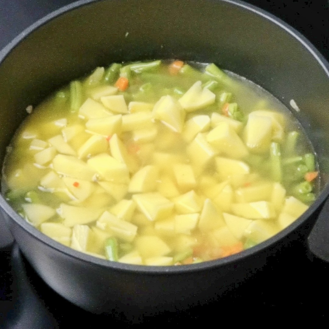 Vegetables and potatoes simmering in a pot.