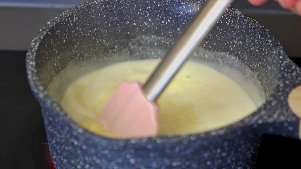 Simmering milk and ingredients for white chocolate syrup while stirring.