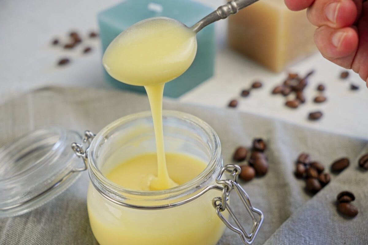 Pouring thick white chocolate coffee syrup into a jar.