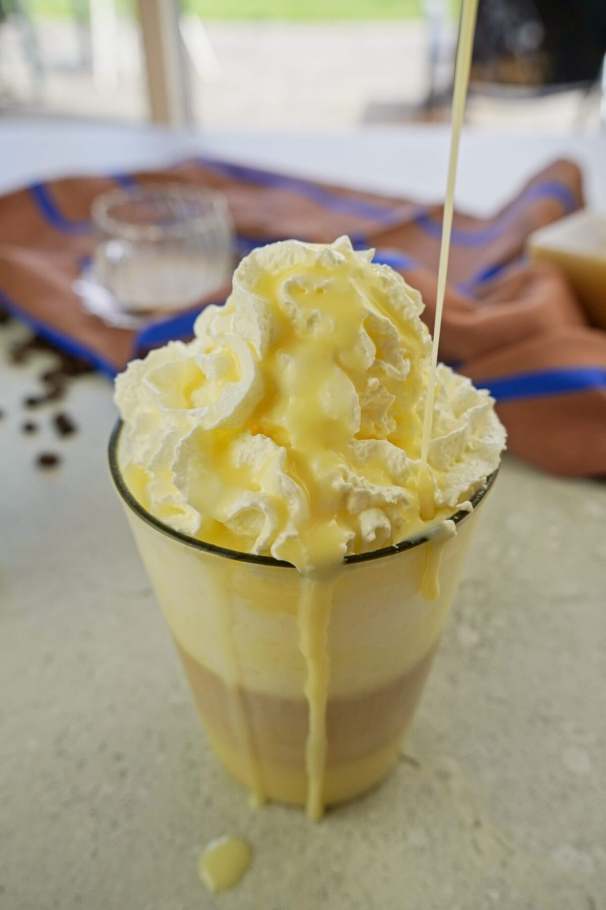 Pouring coffee syrup over a layered latte macchiato.