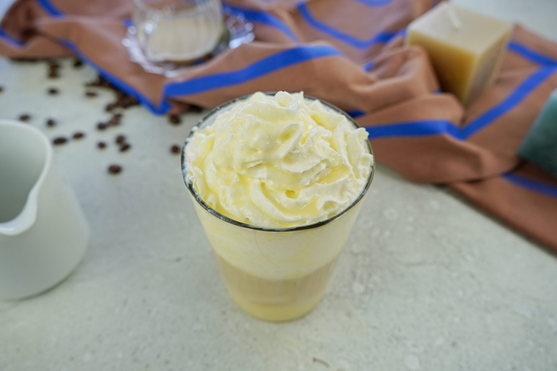 Glass of layered latte macchiato with cream and coffee syrup on a table.